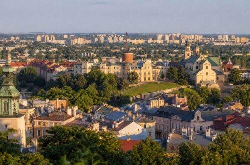 Panorama Lublina — Stare Miasto na wzgórzu i osiedla mieszkaniowe z zielenią w tle.